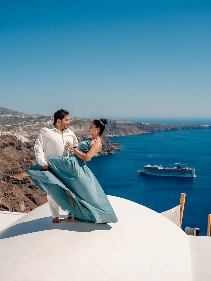 A couple dance on a white terrace high above the deep blue Santorini caldera near Imerovigli