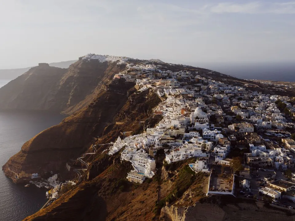 Aerial view over Santorini's caldera and whitewashed clifftop town — the private helicopter and viewpoint experience