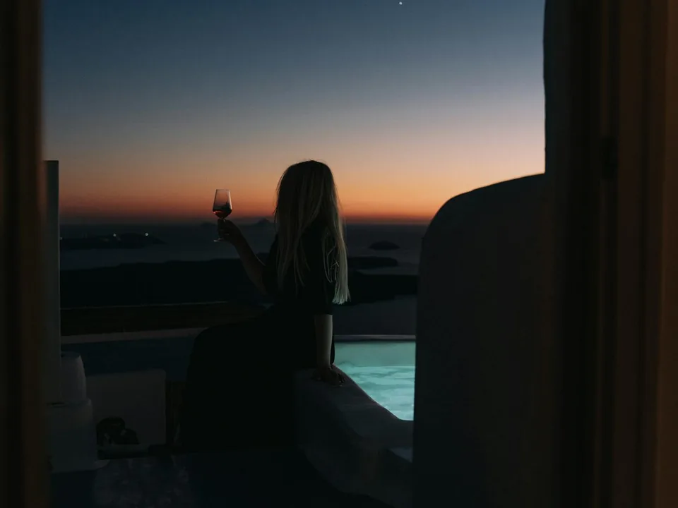 Wine and the caldera at golden hour from a Santorini winery terrace overlooking the Aegean Sea