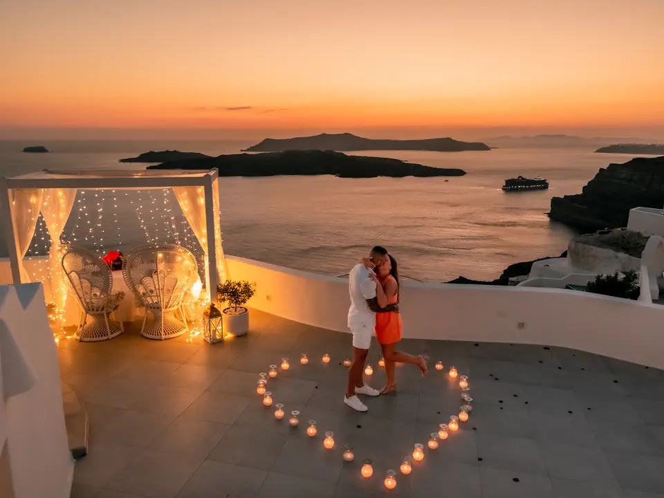 A fairy-lit cabana and candlelit terrace overlooking the Santorini caldera at dusk
