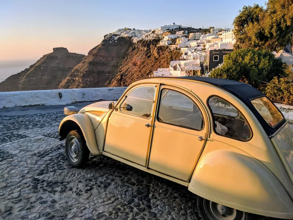 A classic car on a whitewashed Santorini street — a private transfer for your proposal
